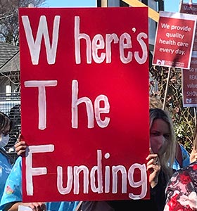Banner at demo that reads 'Where's the funding?'