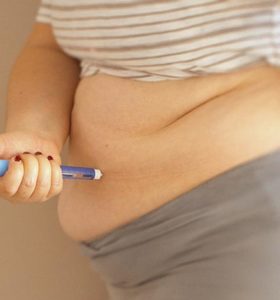 Woman applying diabetes medicine injection into her stomach