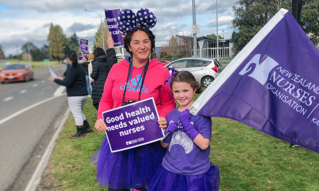 Mum and daughter with 'Good health needs valued nurses' sign