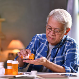 Senior man taking medicine at home.