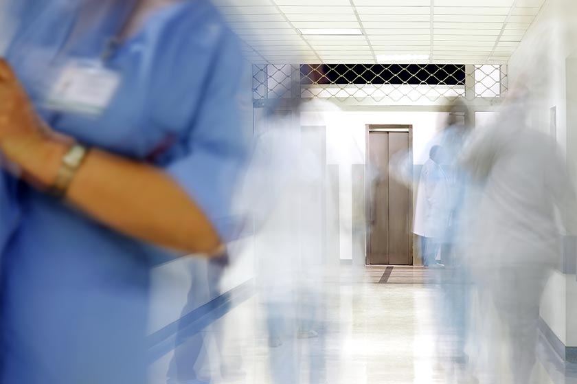 Blurred figures of doctors and nurses in a hospital corridor.
